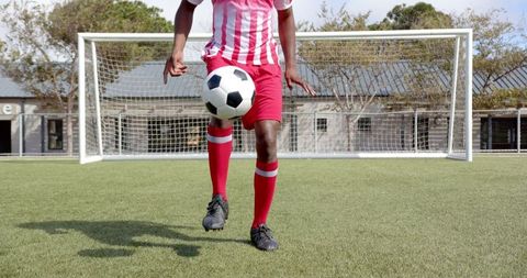 Skillful soccer player juggling ball on field before goal