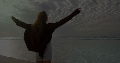 Woman embracing freedom by the ocean at sunset