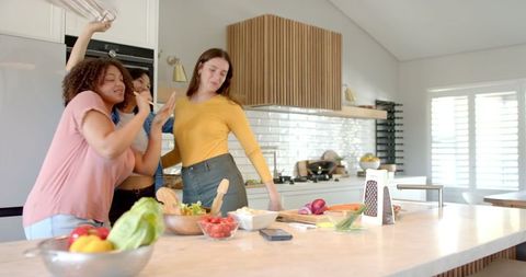Diverse Friends Cooking and Dancing in Modern Kitchen