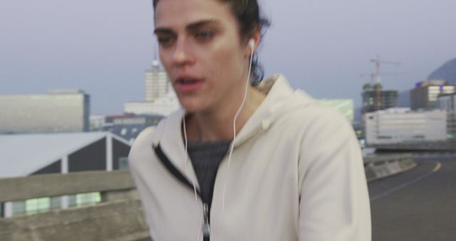 Focused Woman Jogging Outdoors at Dusk with Earphones - Download Free Stock Images Pikwizard.com