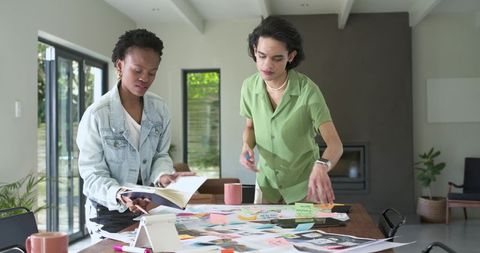 Diverse creatives building moodboard in sunlit home studio workspace