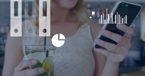 Young woman holding smartphone and sipping mint-lime drink while checking data overlays in cafe