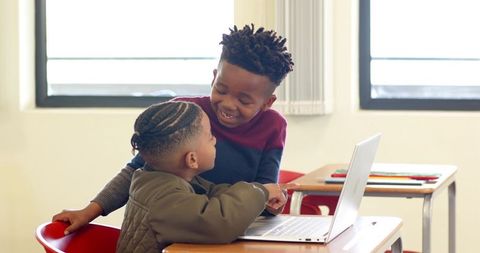 Younger and Older Boys Collaborating on Laptop in Classroom