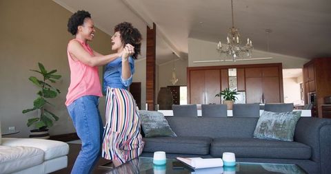 Joyful Female Couple Dancing in Modern Living Room