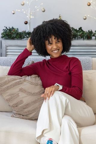 African american woman relaxing on sofa in cozy festive living room wearing burgundy top