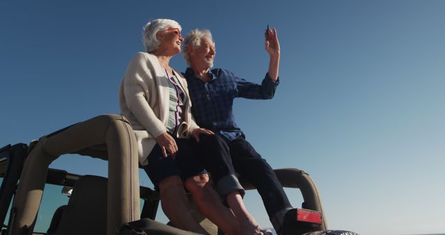 Senior couple enjoying road trip waving from car rooftop - Download Free Stock Images Pikwizard.com