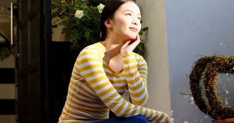 Woman in Striped Top Enjoys Tranquil Moment on Cozy Porch