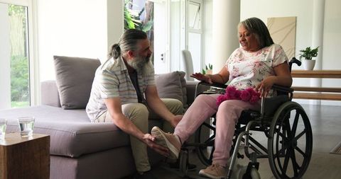 Helpful Partner Adjusting Footrest for Woman in Wheelchair at Home