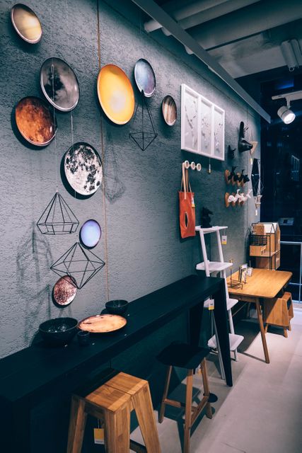 Interior of a modern art gallery showcasing decorative wall plates, geometric hangings, and contemporary furniture. Ideal for illustrating stylish interiors, art exhibitions, and home decor ideas.