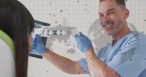 Smiling dentist pointing at dental x-ray on monitor during patient examination in clinic