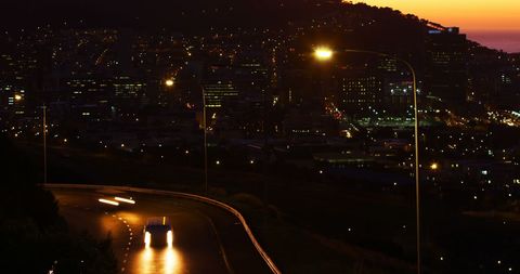 Twilight Cityscape with Car Headlights Illuminating Roadway - Download Free Stock Images Pikwizard.com