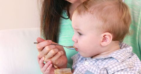 Mother feeding infant healthy baby food nurturing close-up