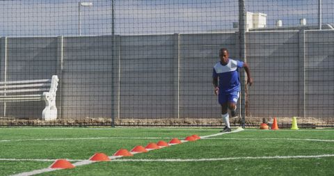 Football Player in Training with Cone Drills on Pitch