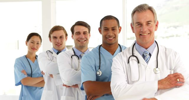 The image shows a diverse group of medical personnel including doctors and nurses standing together and smiling confidently. Their poses and facial expressions suggest unity, teamwork, and professionalism. This image can be used for healthcare-related advertisements, hospital and clinic brochures, websites about medical services, and promotional materials for medical organizations.