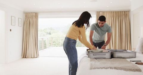 Couple packing suitcase for upcoming vacation at home