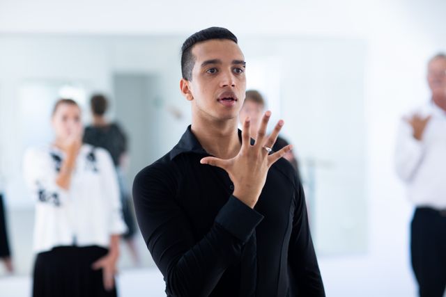 A biracial male dance teacher taking a ballroom dancing class at a dance studio, demonstrating dance moves to a group of seniors. Active golden years hobby.