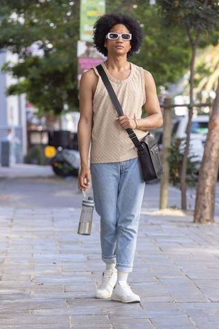 Urban african american man walking with water bottle carrying black messenger bag