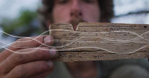 Man holding reclaimed wood plank outdoors emphasizing craftsmanship