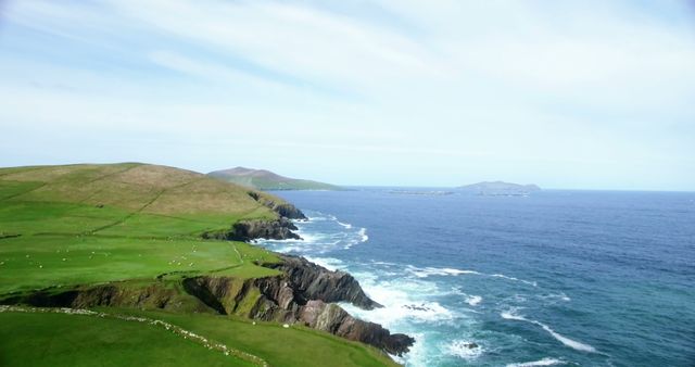 A panoramic view of a lush, green coastline with rolling hills meeting the vibrant blue sea, with copy space. The serene landscape captures the natural beauty of a coastal region, ideal for backgrounds or nature-themed content.