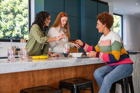 Diverse friends making fruit smoothies in modern kitchen