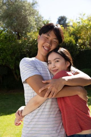Asian Couple Embracing in Sunlit Garden