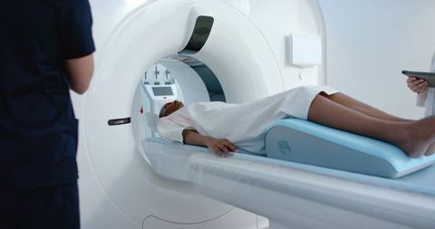 African american woman undergoing mri scan in hospital radiology department with clinicians