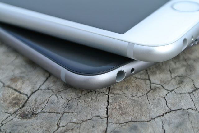 Close-up shows the edges of two stacked smartphones on cracked natural surface, possibly wood or stone. Suitable for illustrating concepts of modern technology, mobile devices, gadget reviews, or advertisements highlighting smartphone design and aesthetics.