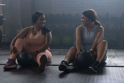 African american women smiling with medicine balls in gym showing partnership and teamwork