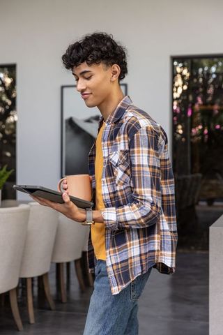 Young male with digital tablet and coffee in modern home interior