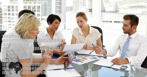 Collaborative business team reviewing tablet and colorful charts at glass office table