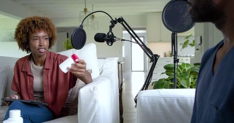 African american woman hosting home podcast holding bottle and talking with co-host