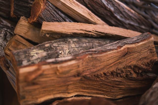 Close-up of stacked firewood logs, showcasing natural textures and details. Ideal for use in holiday-themed content, winter warmth promotions, fireplace advertisements, and rustic home decor ideas.