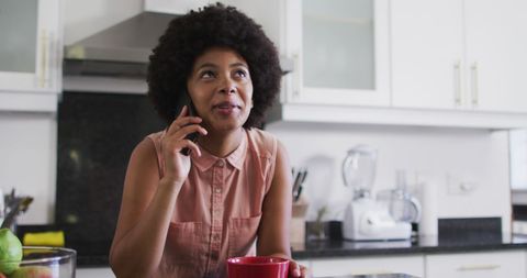 African american woman talking on smartphone in kitchen