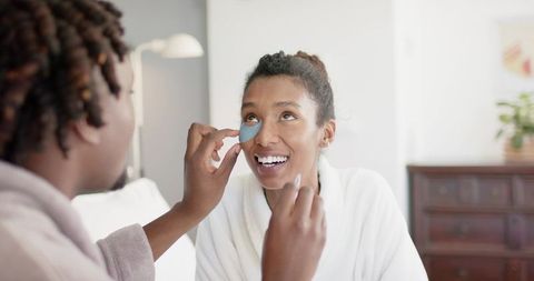African american friends applying blue under-eye gel patches in cozy at-home routine
