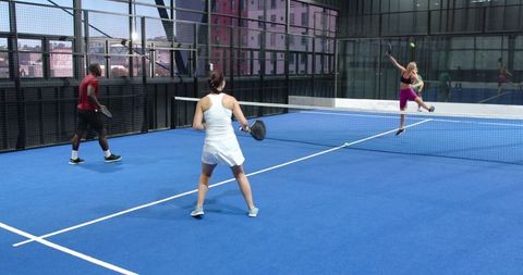 Diverse players engaging in padel game on urban blue court