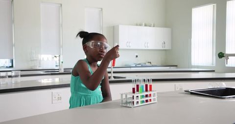 Young student conducting colorful chemistry experiment in modern school laboratory