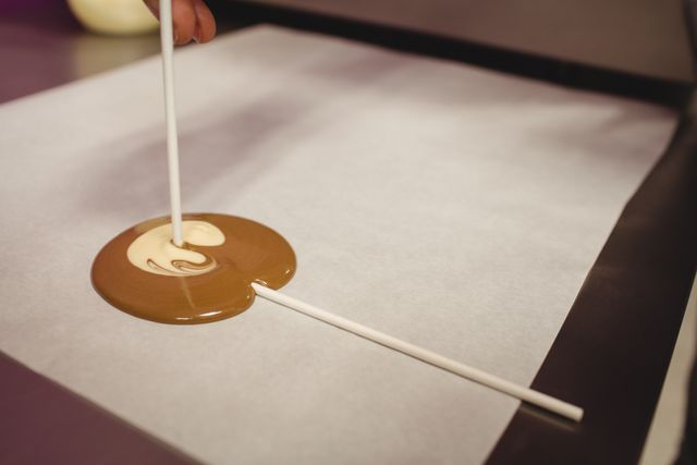 Preparation of lollipop on wax paper in kitchen