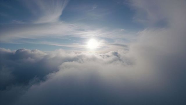 Sun breaking through cloud deck over high-altitude sky, radiant backlit cirrus rays