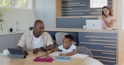 African American Father and Son Learning, Mother Remote Working