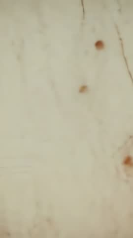 Vertical panning close-up of scratched beige surface with vintage stains and aged texture