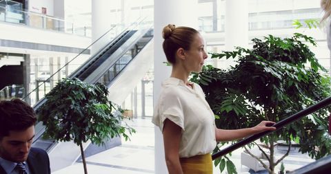 Businesswoman Ascending Escalator in Modern Office Lobby