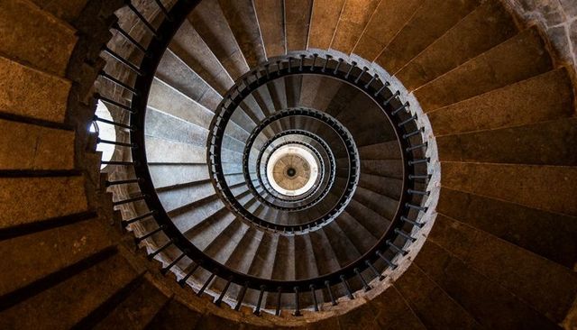 Spiraling Stone Staircase Descending Through Tower Shaft, Showing Worn Steps and Central Light