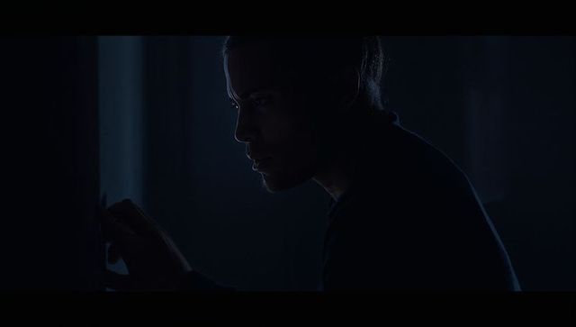 Man pressing light switch in dark room with narrow blue rim light moody profile