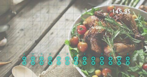 Roast chicken garnished with rosemary on rustic wood tabletop with cherry tomato salad