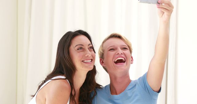 Two friends smiling while taking selfie at home - Download Free Stock Images Pikwizard.com