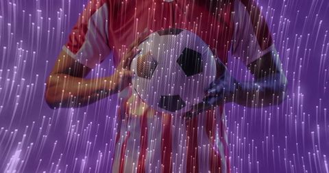 Holding soccer ball and posing under purple neon light trails cinematic sports portrait