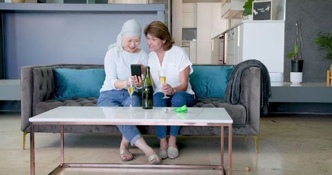 Two Senior Friends Celebrating Friendship with Champagne on Couch
