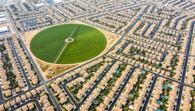 Aerial suburban landscape with center-pivot circular irrigation surrounded by housing grid