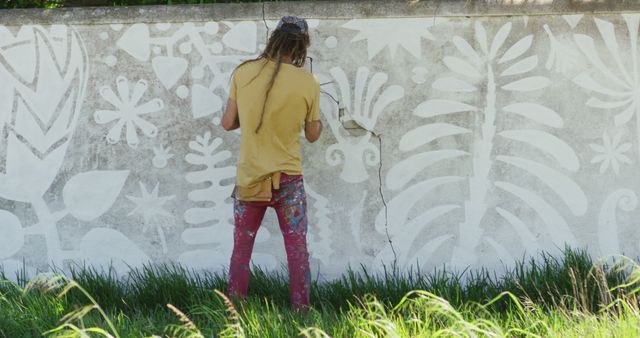 Image of rear view of caucasian male artist with dreadlocks painting mural on wall. Freedom, creativity, inclusivity and hobbies concept digitally generated image.