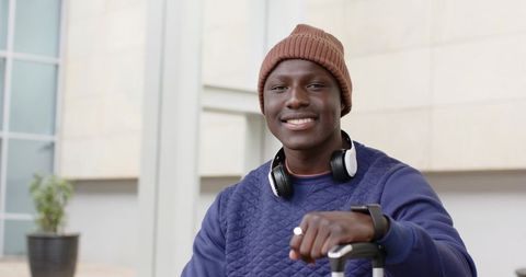 African American Traveler Smiling Wearing Beanie and Headphones With Luggage in Terminal